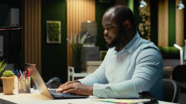 Yorgun erkek personel kollarını ve sırt kaslarını geriyor, zihinsel bulanıklığa ve gece işlerinden bıkkınlık duyuyor. Huzursuz, endişeli ve işlerle boğuşan bir çalışan. Kamera B.