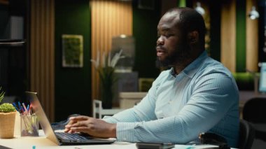 Afrikalı Amerikalı adam diğer masalara bakıyor ve ofiste yalnız olduğunu fark ediyor, fazla mesai yapıyor ve tükenmişlerle uğraşıyor. Uykucu aşırı yüklenmiş kişi gece geç saatlere kadar çalışıyor. Kamera A.