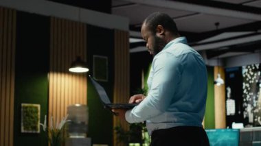 Afrika kökenli Amerikalı bir adam ders kitabına yazmadan önce bir belgeyi düzeltiyor, dizüstü bilgisayardaki raporlardan ana fikirleri ayıklıyor. Gece geç saatlerde belgelendirme uzmanı. Kamera B.