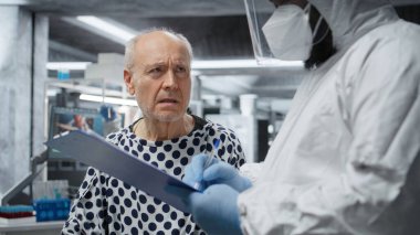 Tehlikeli madde giysisi içindeki doktor bulaşıcı bir hastaya tıbbi bakım uygular. Etkili antiviral antibiyotikler geliştirmek için laboratuarda sağlık verileri kaydeder ve aşı tepkilerini test eder. Kamera A.