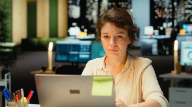 İşletme için rapor güncellemeleri, karanlık bir ofiste gece vardiyasındaki işler için numaraları araştıran ve belgeleyen bir çalışan. Hedeflere ve proje geliştirmeye odaklanıyor. Kamera B.