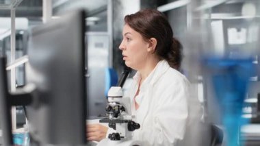 Tükenmiş laboratuvar moleküler biyoloğu bilgisayar masasında geriniyor, DNA hasta verilerini işliyor. Yorgun laboratuvar çalışanı gözlerini kapatıyor, dinlenmek için bilgisayardaki genetik analize ara veriyor, kamera B