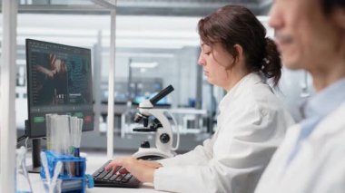 Klinik mikrobiyolog zamanı kontrol ediyor, vardiyanın bitmesini bekliyor, hasta verilerini işliyor. Kol saatini kontrol eden genetik analiz teşhisi için bilgisayar kullanan tanı laboratuarı yöneticisi