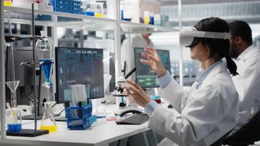 Laboratuvar bilimcisi klinik araştırmalar için DNA hasta verilerini işlemek için sanal gerçeklik teknolojisini kullanıyor. Araştırma tesisi uzmanı laboratuvar genetik analiz yapmak için VR kulaklık kullanıyor, kamera B