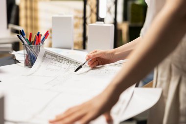 Gayrimenkul yatırım mühendisinin kapatılması planlar ve inşaat planlarını gözden geçirir, modern bir ofisin yerleşim planlarını kontrol eder. Konut geliştirme projesi için imar yönetmelikleri analiz ediliyor.