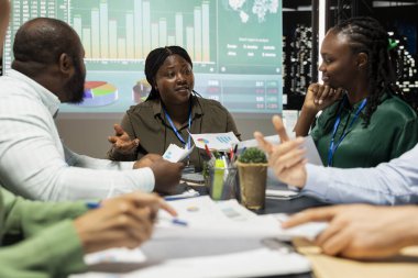 Potansiyel şirket genişleme planlarını inceleyen yönetim kurulu başkanı, ekip amiri ve personel üyeleri veri görselleştirmelerine bakar. Uzmanlar geç saatlerde toplantıda görüşlerini ve fikirlerini paylaşıyorlar.
