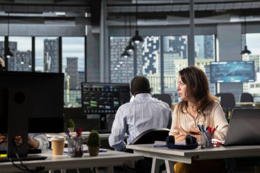 Parlak çalışma alanında dizüstü bilgisayar kullanan iş adamları projeksiyonları, ölçümleri ve raporları analiz ediyorlar. Ekip, yürütme yönetimi altındaki iş istihbaratına, görüşlere ve hedeflere odaklanır.