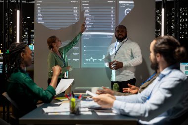 Şirket içindeki performans göstergelerini değerlendiren iş arkadaşları, gece bir hava durumu oturumu düzenleyip eğitim programlarını tartışıyorlar. İşçi takımı geceleri verimliliği artırıyor.