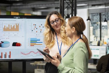 Bir brifing oturumunda kadın iş adamları modern ofiste verimliliği simgeliyor, şirket vizyonunu ve hedeflerini iyileştirmek için analitikleri gözden geçiriyorlar. Profesyonellik ve kurumsal feminizm.