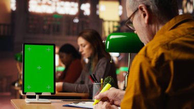 Yaşlı bir adam kütüphanedeki tablette izole edilmiş bir maket ekranı kullanıyor, eğitim belgeleri okuyor ve eğitimini tamamlamaya kendini adamış. Sessiz öğrenim odası son sınıf eğitimi.