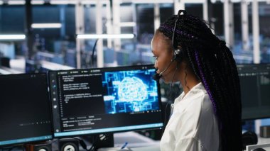 Veri Merkezi bilgisayar bilimcisi kullanıcı teknik desteği sağlamak için yapay zeka asistanı kullanıyor. Sunucu çiftliğindeki Afrikalı Amerikalı kadın yapay zeka ve kamera A 'nın yardımıyla canlı destek aramalarını yönetiyor.