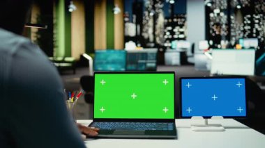 Genç erkek işçi, yeşil ekranı ve mavi ekranı kontrol ediyor. Saatler sonra bütçe ya da finansal projeksiyonlar yapıyor. Ofis çalışanı teknolojiyle önemli görevleri çözüyor. Kamera A.