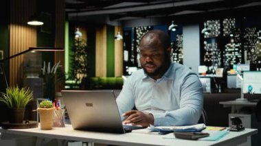 İş yerindeki Afrikalı Amerikalı adam yoğun konsantrasyonda oturup karar vermeyi düşünüyor. Mantıklı düşünme ve sezgilerini uygularken dizüstü bilgisayarını kullanmak, zihinsel bulanıklık. Kamera A.