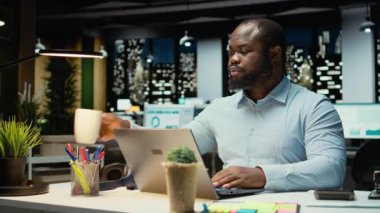 Afrika kökenli Amerikalı erkek analist, gece çalışmaya devam etmek için kahve fincanı içiyor. Ofisteki idari işleri bitirmek için uyanık kalıyor. Mesai bitiminden sonra kafein içeceği yudumlamak. Kamera A.