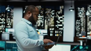 Siyah adam bilgisayardaki raporların ana noktalarını not etmeden ve çıkarmadan önce arşivlenmiş belgeleri inceliyor. Gece geç saatlerde belgelenen analistler. Kamera B.