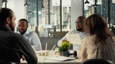 İş toplantısı sırasında müzakere ve proje danışmanlığı yapan çalışma ekibi. Çalışanlar karanlık ofis ortamlarında finans verilerini, ölçümleri ve performans raporlarını analiz etmek için dizüstü bilgisayar kullanırlar. Kamera B.