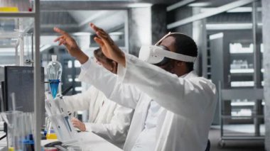Laboratuvarda DNA veri analizi için bilgisayar ve VR kulaklık kullanan bir bilim adamı. Modern laboratuvarda biyoenformatik genomik yazılımı ve sanal gerçeklik teknolojisi kullanan Afrikalı Amerikalı bir adam, kamera B