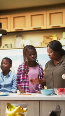 Dikey Video Ebeveynleri ilgilenen çocuklara nasıl ev yapımı pizza yapılacağını öğretiyor, çocuklar işin içinde ve mutfakta birlikte yemek yapmayı öğreniyorlar. Aile hayatı hafta sonu aktivitelerini yakalar