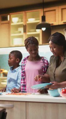 Dikey Videolar Gülümseyen Ebeveynler ve çocuklar ev yapımı aile tarifinden pizza yapmayı öğreniyorlar, anne ve babaları küçük yardımcıları olan çocuklar aşçılık hobilerini öğretiyorlar. Hafta sonu boyunca bağlılık ve kahkaha