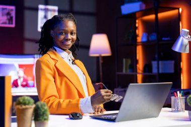 Evdeki bilgisayarla e-posta yazan neşeli bir tele-işçi portresi. Not defterinde yazan neşeli uzaktan çalışan, bitirilmiş proje evraklarını teslim etmek için belgeler hazırlayan