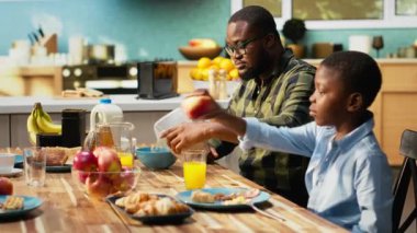 African american father interrupting breakfast meal to answer a phone call, neglecting his family and being busy at home. Working dad ignoring son and daughter at the table. Camera B.