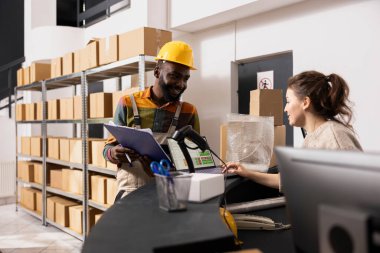 İki işçi, ihracat ve toptan satış siparişleri için mallar hazırlarken, kalite kontrol işlemleri ve envanter listesini kontrol ediyorlar. Çevrimiçi alışveriş için perakende ürün teslimatı.