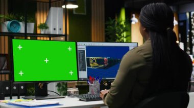 Ofiste birden fazla monitör kullanarak oyun geliştirme üzerinde çalışan Afrikalı Amerikalı kadının yanındaki yeşil ekran. Kadın mühendis yazılımda fütüristik bir uzay gemisi istasyonu yaratıyor. Kamera B.