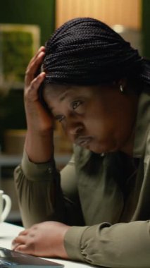 Dikey Video Afrikalı Amerikalı kadın masasında saatlerce oturduktan sonra yorgun düşmüş, başı avucunda uyuyakalmış. Bunalmış endişeli ve yorgun işçiler tükenmişlik ve zihinsel çöküntülerle uğraşır.