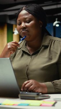 Dikey video Afrikalı Amerikalı analist, dizüstü bilgisayarla ilgili bir ikilemin olası çözümlerini merak ediyor, hem mantıksal çıkarım hem de sezgisel gözlem ile projeksiyonları değerlendirmek için yoğun konsantrasyon