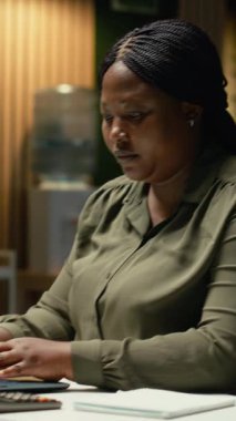 Dikey Video Kadın Çalışanı pozu düzeltiyor ve boyun kaslarını esnetiyor, yaslanmış sandalyeye yaslanıyor ve kas gevşemesi için sırt masajı yapıyor. Kişi, sertlik nedeniyle moladan zevk alıyor