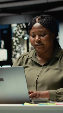 Dikey Afrikalı Amerikalı kadın dizüstü bilgisayarını ve ofis lambasını kapatıyor, binayı terk etmeye hazırlanıyor, gece yarısı evine gidiyor. Çalışanlar mesai saatleri dışında, karanlık uzayda yalnız çalışıyorlar. Kamera B.