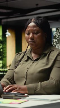 Dikey Video Yöneticisi, taktiksel bir çözüm öngörüyor ve kalemle oynuyor. Mesai saatleri dışında masasında çalışıyor. Eleştirel düşünen, farklı bakış açıları için seçenekleri değerlendiren bir kadın.