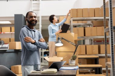 Afrikalı Amerikalı personel, küçük bir işletmenin envanter odasında mal paketlemeyi denetliyor, dağıtım operasyonları. Siparişleri yönetmek ve ürünleri hızlı teslimat için hazırlamak.