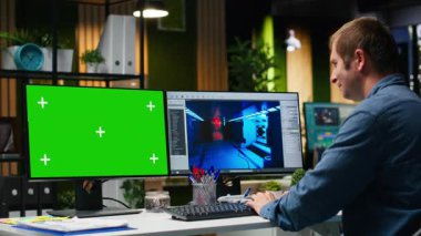 Krom anahtar, erkek çalışan oyun geliştirme üzerinde çalışıyor, çalışma istasyonunda çift monitör kullanıyor. Genç uzman mühendis modern yazılımda fütürist uzay gemisi istasyonu yaratıyor. Kamera B.