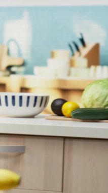 Ahşap yemek mobilyaları ve modern aletleri olan dikey video boş mutfak. Tezgahta renkli sebzeler, taze meyve ve baharatlar sergileniyor, rahat atmosferi olan şık bir evi temsil ediyor..