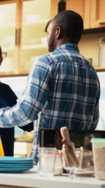 Dikey Video Sevecen siyah çift mutfakta güzel bir vals yapıyor, güne romantik bir an ve bir aşk şarkısıyla başlıyor. Yavaş dans ve el ele tutuşmalar, samimi bir bağ. Kamera B