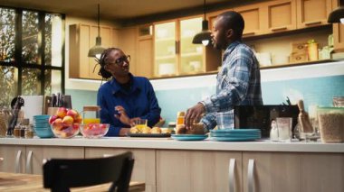 Afro-Amerikan çifti, ekmeği tost makinesinden çıkarıyorlar ve kahvaltıyı evde sabahların güzelliğiyle sağlıklı bir yaşam tarzı için yapıyorlar. Birliktelik. Kamera A.