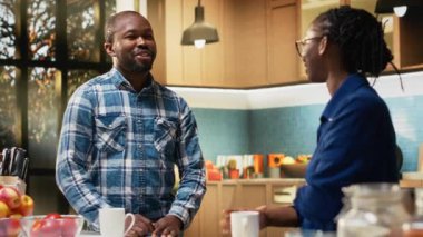 Mutfak tezgahında duran, sağlıklı bir kahvaltıyı hamur işi ve kahveyle servis eden neşeli siyah kadın portresi. Genç yetişkin, sabah rutininin ev yapımı yemeklerine odaklanıyor. Kamera B.