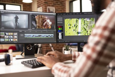 Afrika kökenli Amerikalı video editörü film görüntülerini ve zaman çizelgelerini düzenlemek için birden fazla ekran düzeneği kullanıyor. Erkek prodüksiyon sanatçısı iş akışını düzenleme konusunda yaratıcı kararlar alıyor.