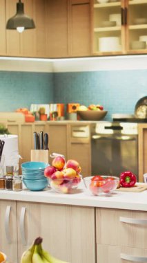 Ahşap yemek mobilyaları ve modern aletleri olan dikey video boş mutfak. Tezgahta renkli sebzeler, taze meyve ve baharatlar sergileniyor, rahat atmosferi olan şık bir evi temsil ediyor..