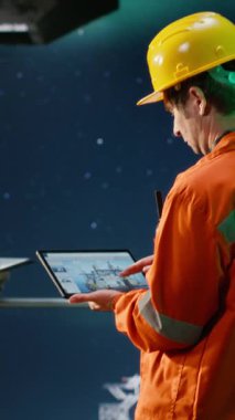 Vertical Video Offshore mühendisi denizaşırı platformda petrol üretimini izliyor, performans için emisyon takibini değerlendirmek için tablet kullanıyor. Kuzeyde petrol ve gaz sondaj operasyonlarının sağlanması