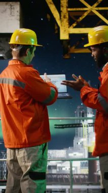 Dikey video çevre memurları aurora borealis altındaki kıyı petrol platformunu inceleyerek, dizüstü bilgisayarla benzin çıkarma mühendisliğini izliyor. Okyanustan petrol üretim stratejisi. Kamera.