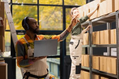 E-dükkan çalışanı kulaklıkla en sevdiği müziği dinliyor ve paketleri sayıyor, kalite kontrol ve dizüstü bilgisayarla envanter kontrolü yapıyor. Ev lojistiği ile e-ticaret sevkiyatları.
