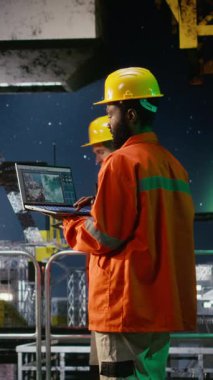 Dikey Video Afrikalı Amerikalı işçiler gece kıyı sondaj kulesinde doğal gaz ve petrol çıkarma kurallarına uyulmasını sağlamak için teftiş ve emisyon takibi yapıyorlar. Kamera A.