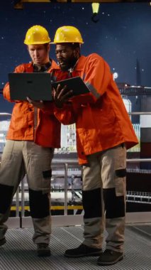 Dikey Görüntü Offshore çeşitli işçiler sondaj sondaj sistemlerini laptop ve tabletle izleyerek, endüstriyel platformdan doğalgaz ve petrol çıkarmayı yönetirler. Petrol ve gaz endüstrisi. Kamera A.