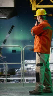 Petrol üretim operasyonları sırasında telsiz aracılığıyla koordinasyon sağlayan dikey video Offshore mühendisi, kuzey ışıkları altında doğal gaz emisyonu izleme. Petrol çıkarma kurallarına uymak. Kamera A.