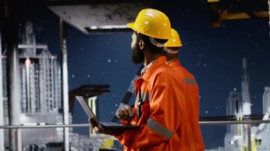 Siyah denizaşırı işçiler petrol platformunda sondaj sondajı güvenliğini artırmak için modern teknoloji ve dizüstü bilgisayar kullanarak risk değerlendirmesi yapıyorlar. Fosil yakıtlar ve doğal gaz çıkarma. Kamera B.