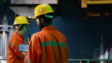 Çevre memuru kuzey ışıkları altında kıyı sondajında tablet kullanarak platformda petrol ve yakıt alımını sağlıyor. Petrol ve gaz üretim endüstrisine uyum. Kamera B.