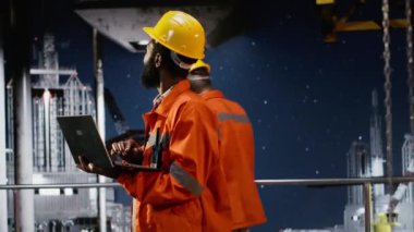 Bir platformdaki profesyonel fosil yakıtlar ve petrol çıkarma üzerine odaklanarak, deniz aşırı sondaj sondajı operasyonunu laptopla izleyen sanayi işçisi. Doğal gaz ve petrol endüstrisi. Kamera B.