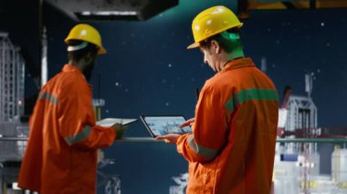 Offshore mühendisi denizaşırı platformda petrol üretimini izliyor, performans için emisyon takibini değerlendirmek için tablet kullanıyor. Kuzey ışıkları altında petrol ve gaz sondaj operasyonlarını sağlama almak. Kamera B.